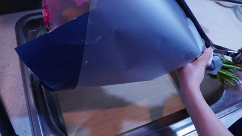 Cutting Tape to Open Wrapped Bouquet Over Sink Stock Footage 319920120