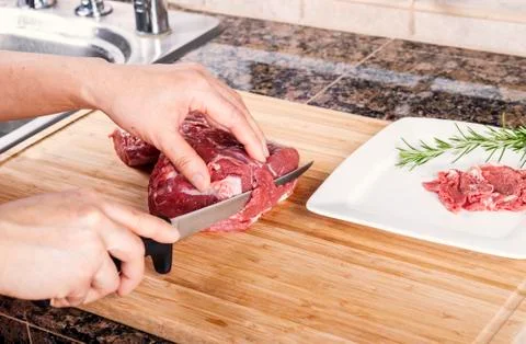 Cutting thin slices of lean red lamb meat Stock Photos