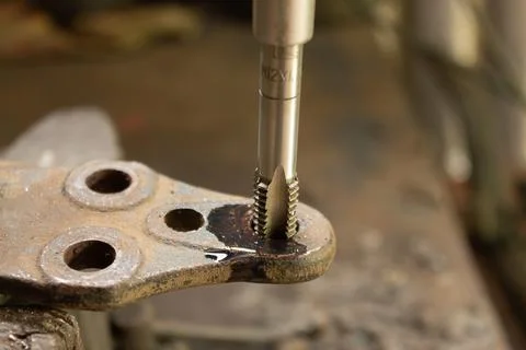 Cutting a thread in a hole with a tap by hand. Material high speed steel. We  Stock Photos