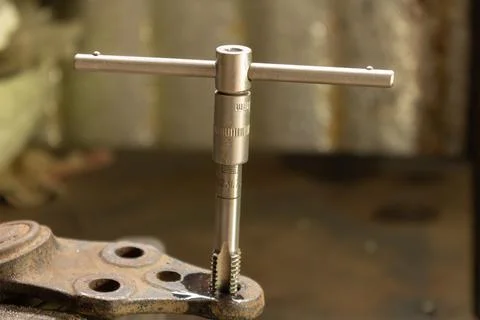 Cutting a thread in a hole with a tap by hand. Material high speed steel. We  Stock Photos