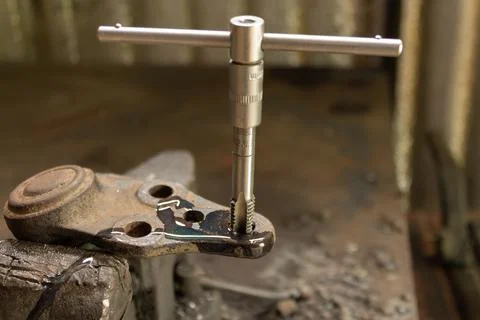 Cutting a thread in a hole with a tap by hand. Material high speed steel. We  Stock Photos