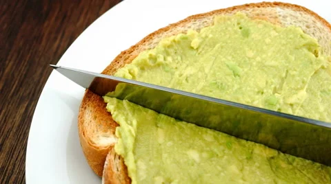 Cutting toast spread with mashed avocado in half Stock Footage 46956051
