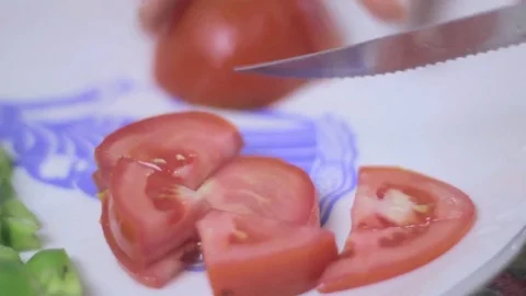 Cutting a tomato into chunks in a plate with a blue sign Stock Footage 75612398