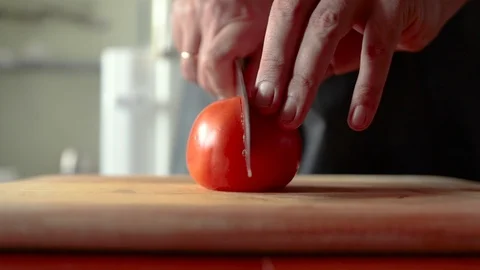 Cutting a tomato in half on a cutting board Stock Footage 118078099