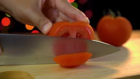 Cutting a tomato with kitchen knife in light bokeh background Stock Footage 92083324
