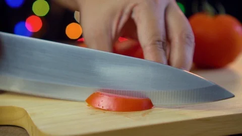Cutting a tomato with kitchen knife in light bokeh background Stock Footage 92084321