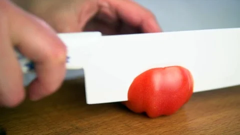 Cutting a tomato with a white ceramic knife Stock Footage 75566824