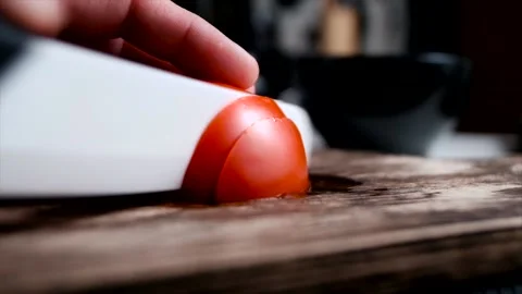 Cutting tomato with white ceramic knife on a rustic wooden board Stock Footage 140368201