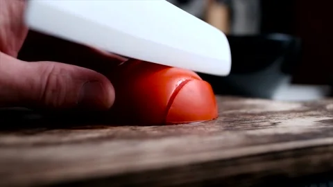 Cutting tomato with white ceramic knife on a rustic wooden board Stock Footage 140368213
