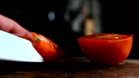 Cutting tomato with white ceramic knife on a rustic wooden board Stock Footage 140369994