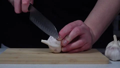 Cutting the top off a whole garlic head close-up Stock Footage 334191130