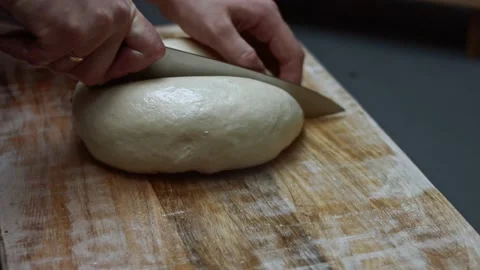 Cutting in two fresh raw dough for pizza on wooden cutting board. Preparing Stock Footage 146653913