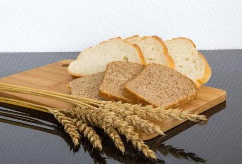 Cutting two types of bread with wheat ears on wooden Board Stock Photos