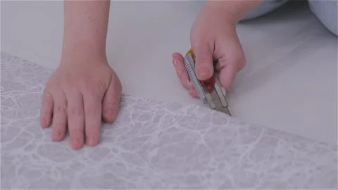 Cutting wallpaper into strips for hanging in a room. Trimming excess paper. Stock Footage 332018917