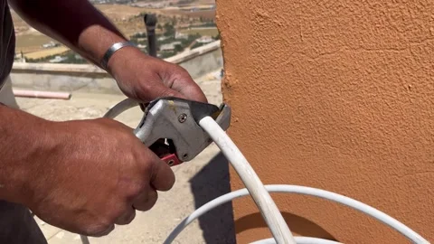 Cutting a White Plastic Pipe with a Cutter Tool Stock Footage 345209890