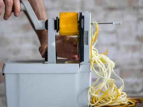Cutting a yellow zucchini using a spiralizer. Stock Photos