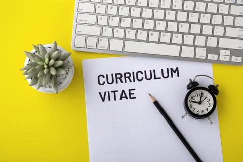 CV with computer keyboard and clock on yellow background Stock Photos