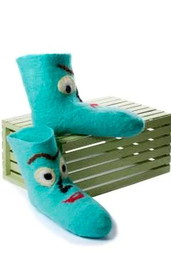 Cyan felt socks with a pattern on a white background on a wooden box Stock Photos