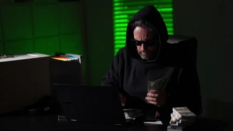 Cyber attack with unrecognizable hooded hacker counting money. network security Stock Footage 320024964