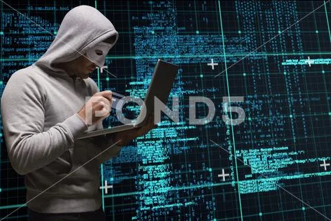 Cyber criminal is holding a credit card and a laptop against matrix code rain Stock Photos
