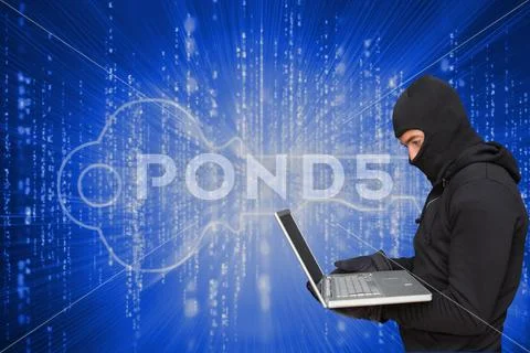 Cyber criminal wearing an hood is hacking a laptop against matrix code Stock Photos
