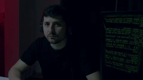 Cyber security analyst, focused and alert, monitors computer screen displaying Stock Footage 323322800