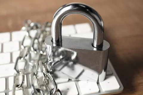 Cyber security. Keyboard with padlock and chain on wooden table, closeup 写真素材