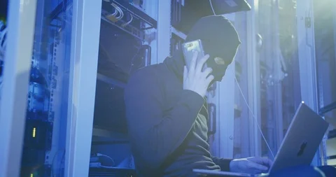 Cybercrime, hacking and technology concept - male hacker in server room using Stock Footage 107901794