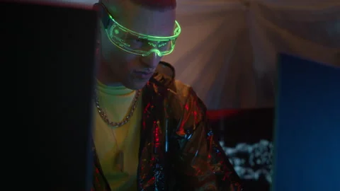 Cyberpunk Man in Shiny Jacket and Smart Glasses Hacking on Computer in Neon Room Stock Footage 327632769
