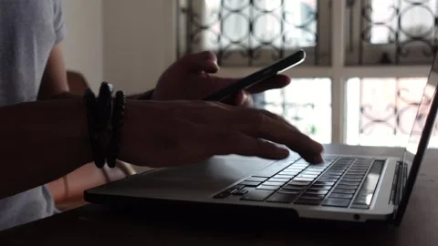 Cybersecurity 2FA login concept. A man logs in using a smartphone and laptop Stockbeeldmateriaal 314442915
