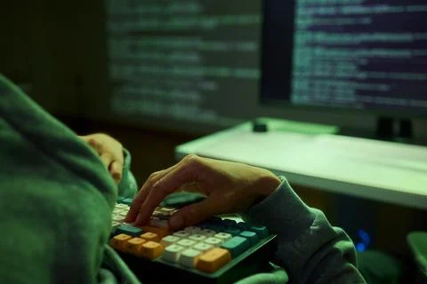 Cybersecurity Analyst Engaged in Writing Code Within a Dimly Lit Environment for Foto stock