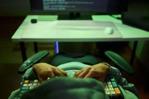 Cybersecurity Analyst Engaged in Writing Code Within a Dimly Lit Environment for Stock Photos