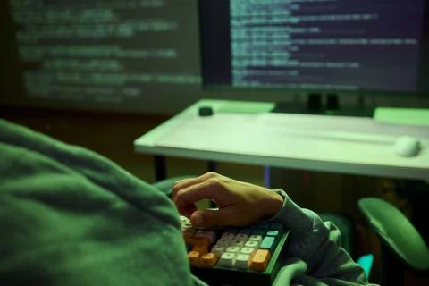 Cybersecurity Analyst Engaged in Writing Code Within a Dimly Lit Environment for 库存照片