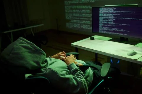 Cybersecurity Analyst Engaged in Writing Code Within a Dimly Lit Environment for Stock Photos