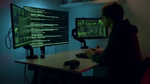 Cybersecurity analyst, focused on multiple screens displaying code and data Stock Footage 322549052