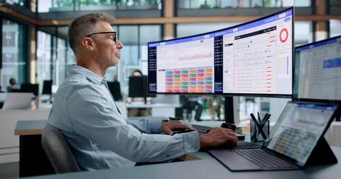 Cybersecurity Analyst Monitors Cloud Risk Dashboards Using Dual Touchscreen L Stock Photos