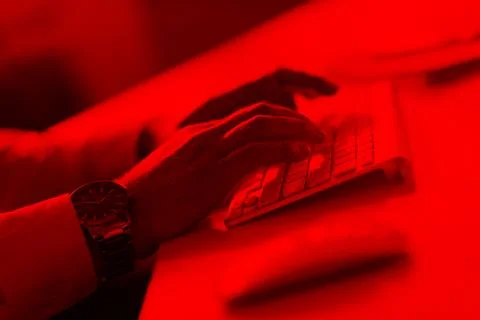 Cybersecurity Hacker Typing on Keyboard in Red Light 스톡 사진