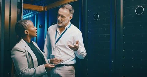 Cybersecurity, tablet and talking with people in server room together for p.. Stock Photos