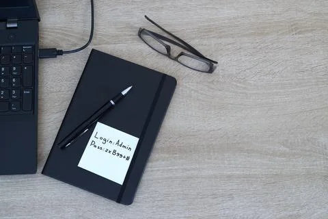 Cybersecurity vulnerability - Password written on sticky note on office desk. Stock Photos