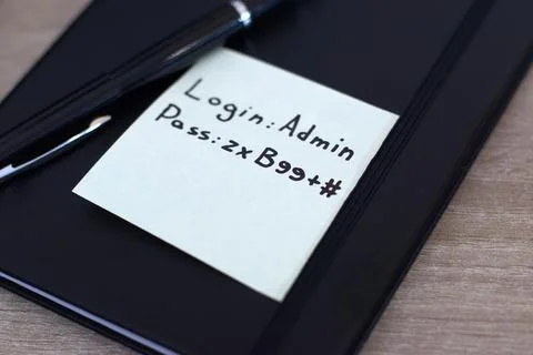 Cybersecurity vulnerability - Password written on sticky note on office desk. Stock Photos