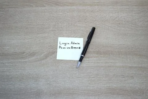 Cybersecurity vulnerability - Password written on sticky note on office desk. Stock Photos