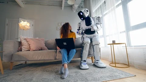 Cyborg and human concept. Young woman and cyborg working with a laptop. Stock Footage 114964390