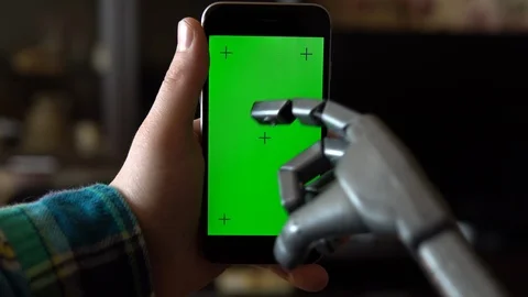 Cyborg uses the phone. A gray mechanical hand is pressing on a smartphone with a Stock Footage 126862298