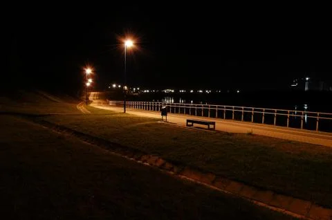The cycle path in the night city on the river bank lit by lamps Stock Photos