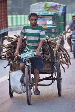 Cycle rickshaw driver hauling goods through city traffic Stock Photos