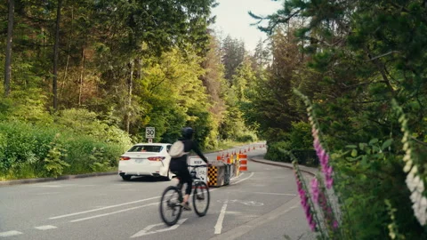 Cyclist and car driving through Stanley Park, Vancouver BC Stock Footage 244542419