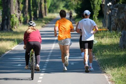 Cyclist and runners using shared park trail in summer Stock Photos