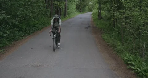 Cyclist approaches camera on forest road with empty space Stock Footage 311919823