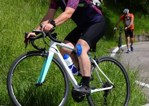 Cyclist with an athletic taping patch on their knee and a cyclist with a fl.. Fotos de archivo