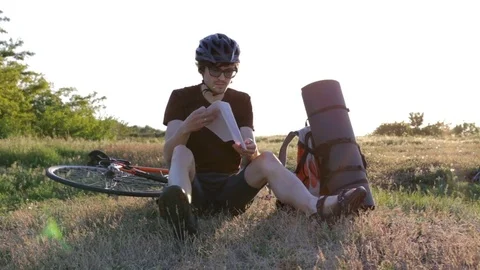 A cyclist atop a mountain looks at a route map Stock Footage